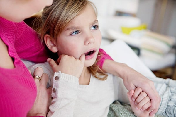 девочка трогает зуб при травматическом стоматите